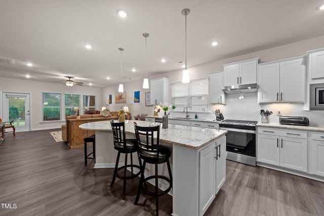 2370 Friars Head Ct, Fuquay Varina, NC 27526 - kitchen with stainless steel stove, under cabinet range hood, a center island, a breakfast bar, and white cabinetry