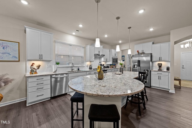 2370 Friars Head Ct, Fuquay Varina, NC 27526 - kitchen with stainless steel appliances, a breakfast bar area, dark wood finished floors, a kitchen island, and white cabinets
