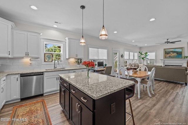 829 Warwick Ln, Carthage, NC 28327 - kitchen with stainless steel dishwasher, white cabinets, open floor plan, wood finished floors, and ornamental molding