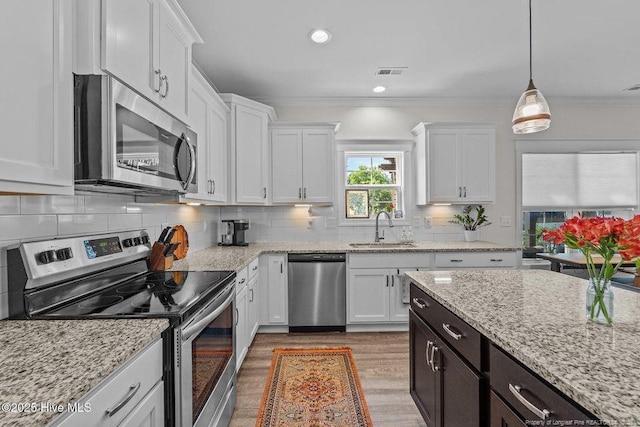 829 Warwick Ln, Carthage, NC 28327 - kitchen with appliances with stainless steel finishes, white cabinets, wood finished floors, ornamental molding, and tasteful backsplash