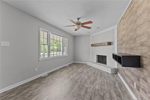 801 Algood Ave, Hope Mills, NC 28348 - unfurnished living room featuring a ceiling fan, a textured ceiling, wood finished floors, and a brick fireplace