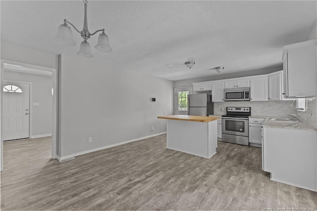 801 Algood Ave, Hope Mills, NC 28348 - kitchen featuring appliances with stainless steel finishes, a center island, wood finished floors, white cabinetry, and a textured ceiling