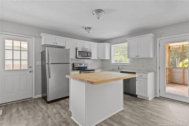 801 Algood Ave, Hope Mills, NC 28348 - kitchen featuring stainless steel appliances, butcher block countertops, light wood-style floors, decorative backsplash, and a textured ceiling