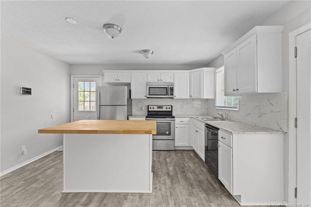 801 Algood Ave, Hope Mills, NC 28348 - kitchen featuring appliances with stainless steel finishes, butcher block countertops, a kitchen island, light wood-style flooring, and a textured ceiling