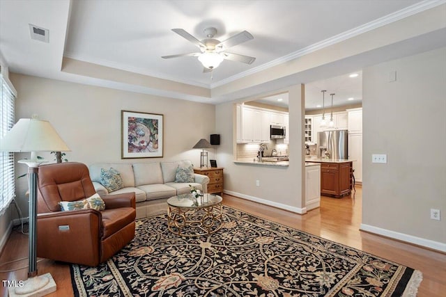 4742 Ludwell Branch Ct, Raleigh, NC 27612 - living room with light wood-style floors, ceiling fan, ornamental molding, and a tray ceiling