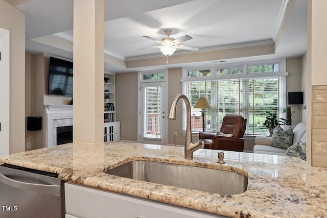 4742 Ludwell Branch Ct, Raleigh, NC 27612 - kitchen with crown molding, stainless steel dishwasher, a raised ceiling, a premium fireplace, and light stone counters