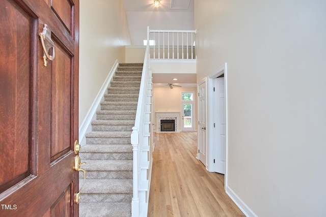 119 Heatherwood Dr, Apex, NC 27502 - entrance foyer with a fireplace, stairs, light wood-style floors, ceiling fan, and a high ceiling