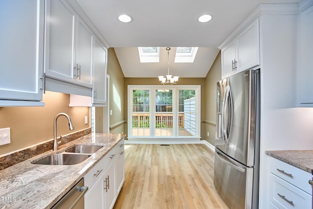 119 Heatherwood Dr, Apex, NC 27502 - kitchen with stainless steel appliances, a skylight, white cabinetry, light wood-style floors, and light stone counters