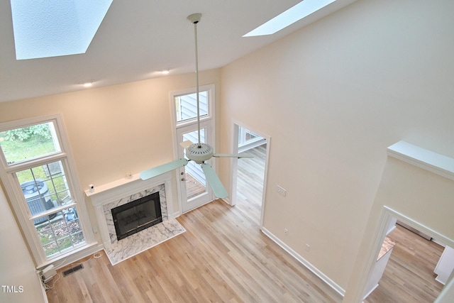 119 Heatherwood Dr, Apex, NC 27502 - unfurnished living room with a skylight, a premium fireplace, light wood-style flooring, plenty of natural light, and a towering ceiling
