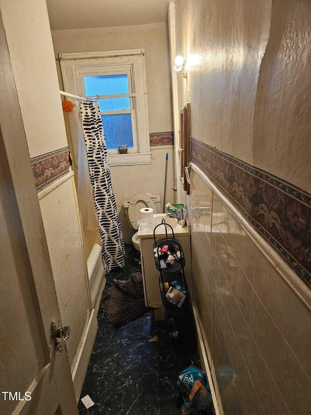 2928 N Patterson Ave, Winston-Salem, NC 27105 - bathroom featuring a wainscoted wall, marble look tile flooring, and shower / tub combo with curtain