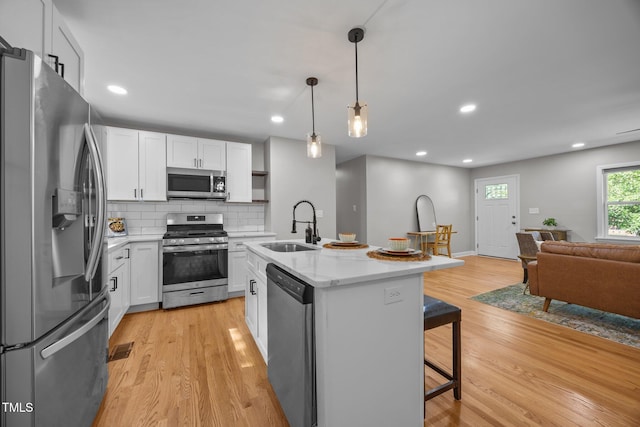4011 Garrett Rd, Durham, NC 27707 - kitchen featuring stainless steel appliances, open floor plan, a breakfast bar, light wood-style floors, and white cabinetry