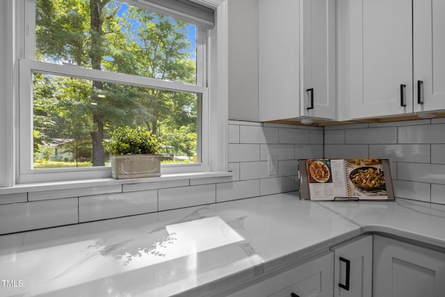 4011 Garrett Rd, Durham, NC 27707 - kitchen with white cabinetry, backsplash, plenty of natural light, and light stone counters