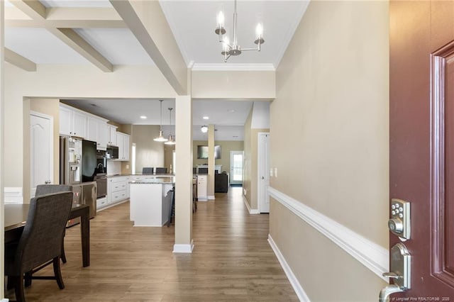 1657 Stackhouse Dr, Fayetteville, NC 28314 - kitchen featuring stainless steel appliances, wood finished floors, a chandelier, white cabinetry, and ornamental molding