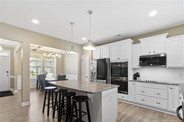 1657 Stackhouse Dr, Fayetteville, NC 28314 - kitchen featuring appliances with stainless steel finishes, a chandelier, a center island, light stone countertops, and tasteful backsplash