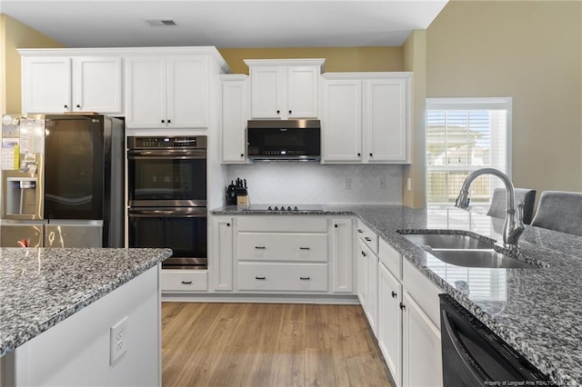 1657 Stackhouse Dr, Fayetteville, NC 28314 - kitchen with black appliances, white cabinets, backsplash, light wood-style floors, and stone countertops