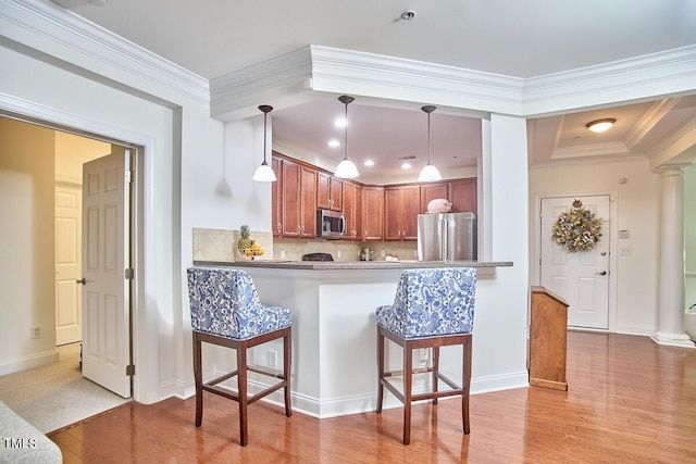 10410 Rosegate Ct Unit 105, Raleigh, NC 27617 - kitchen with stainless steel appliances, light wood-style floors, a breakfast bar area, decorative columns, and decorative backsplash