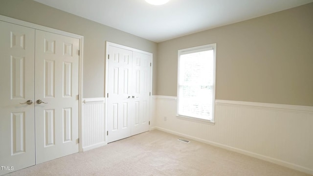 8001 Flanagan Pl, Raleigh, NC 27612 - unfurnished bedroom with a wainscoted wall, multiple windows, two closets, and carpet flooring