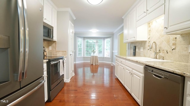 8001 Flanagan Pl, Raleigh, NC 27612 - kitchen featuring stainless steel appliances, crown molding, white cabinetry, backsplash, and hardwood / wood-style floors