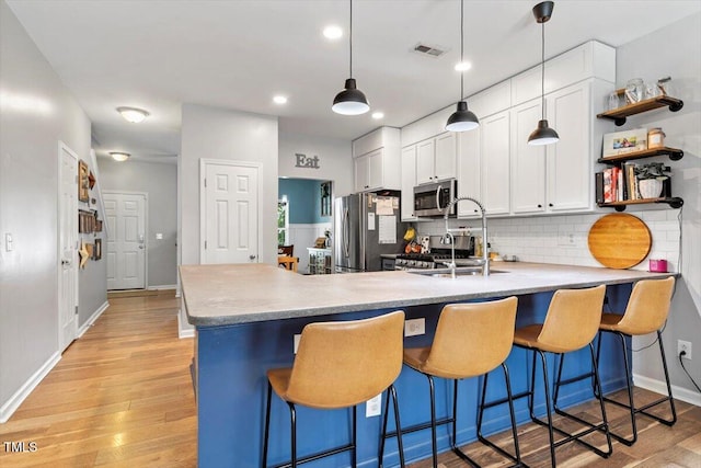 109 Covenant Rock Ln, Holly Springs, NC 27540 - kitchen featuring stainless steel appliances, a peninsula, light wood-type flooring, decorative backsplash, and light countertops