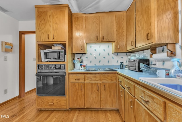 128 Chris Ct, Garner, NC 27529 - kitchen featuring black oven, cooktop, light countertops, and light wood finished floors
