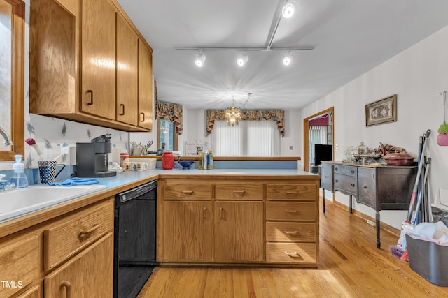128 Chris Ct, Garner, NC 27529 - kitchen with black dishwasher, light countertops, a peninsula, light wood-type flooring, and a chandelier