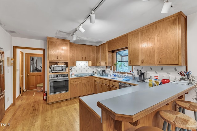 128 Chris Ct, Garner, NC 27529 - kitchen with black oven, stainless steel microwave, light wood-type flooring, track lighting, and light countertops