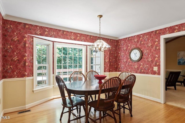 8704 Mill House Ln, Bahama, NC 27503 - dining area with wallpapered walls, a chandelier, light wood-type flooring, a wainscoted wall, and crown molding