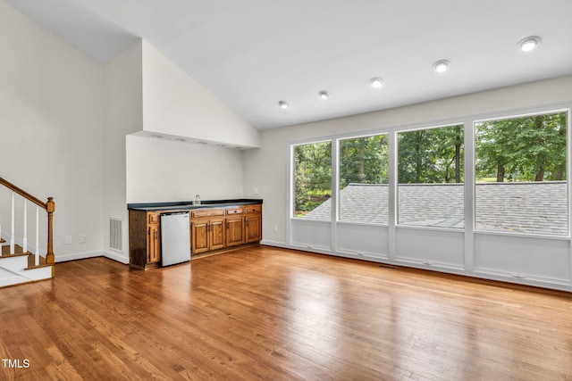 1820 Hunting Ridge Rd, Raleigh, NC 27615 - kitchen with healthy amount of natural light, dishwasher, vaulted ceiling, brown cabinetry, and wood finished floors