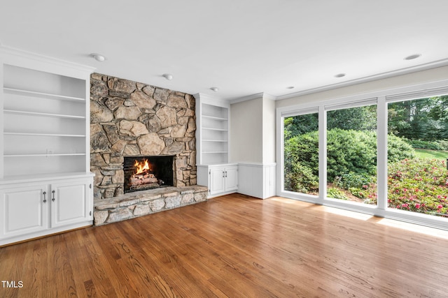 1820 Hunting Ridge Rd, Raleigh, NC 27615 - unfurnished living room with built in shelves, wood finished floors, a stone fireplace, and crown molding