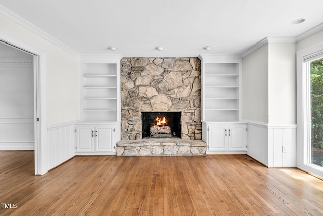 1820 Hunting Ridge Rd, Raleigh, NC 27615 - unfurnished living room with built in features, light wood-type flooring, a fireplace, a wainscoted wall, and crown molding
