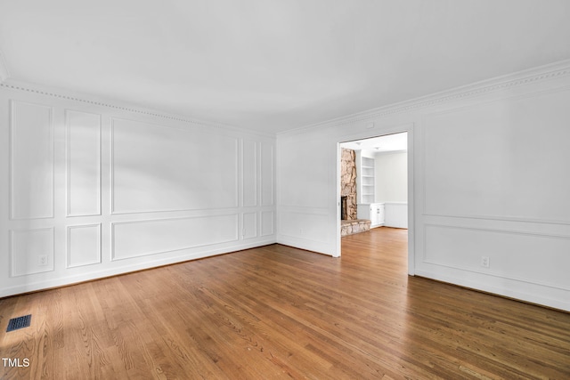 1820 Hunting Ridge Rd, Raleigh, NC 27615 - unfurnished room with a decorative wall, crown molding, built in shelves, wood finished floors, and a fireplace