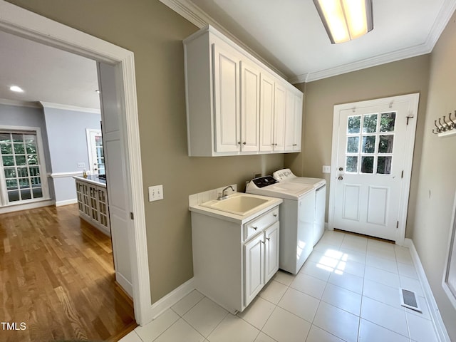 21 Covington Ln, Durham, NC 27712 - laundry room featuring cabinet space, crown molding, healthy amount of natural light, washing machine and clothes dryer, and light wood-style flooring