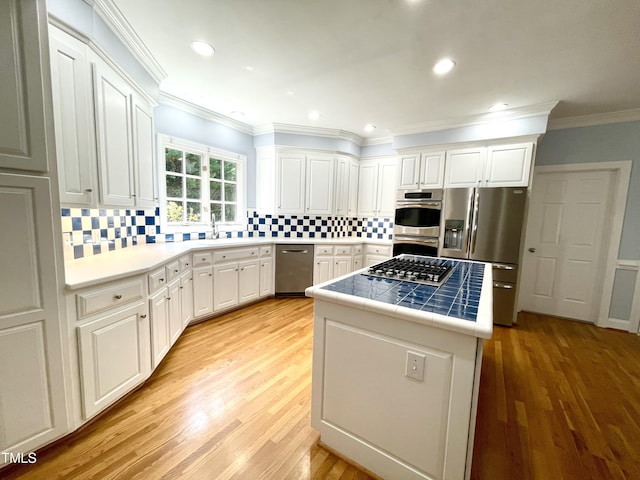 21 Covington Ln, Durham, NC 27712 - kitchen with appliances with stainless steel finishes, tile countertops, white cabinetry, crown molding, and decorative backsplash
