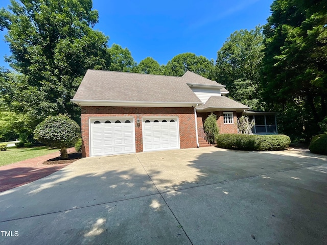 21 Covington Ln, Durham, NC 27712 - view of front of house featuring concrete driveway, brick siding, an attached garage, and a sunroom