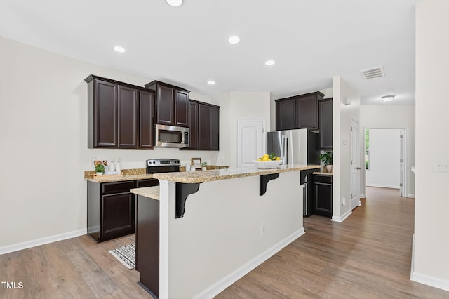 4520 Middletown Dr, Wake Forest, NC 27587 - kitchen featuring stainless steel appliances, a breakfast bar, dark brown cabinetry, light wood-style flooring, and recessed lighting