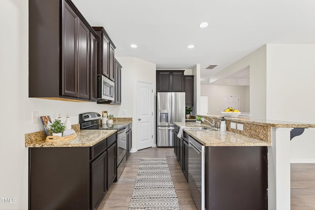 4520 Middletown Dr, Wake Forest, NC 27587 - kitchen with stainless steel appliances, light wood finished floors, dark brown cabinetry, light stone countertops, and recessed lighting