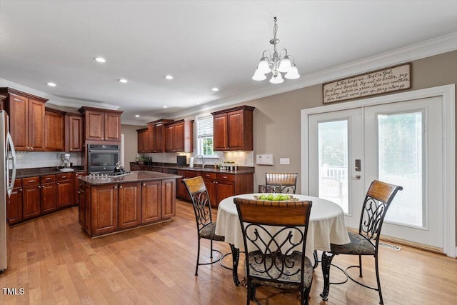 7804 Percussion Dr, Apex, NC 27539 - kitchen with ornamental molding, a chandelier, dark countertops, decorative backsplash, and light wood finished floors