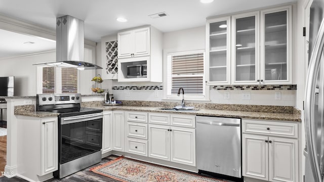 304 Spring St, Durham, NC 27703 - kitchen with appliances with stainless steel finishes, island exhaust hood, white cabinetry, backsplash, and ornamental molding