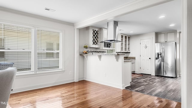 304 Spring St, Durham, NC 27703 - kitchen with stainless steel refrigerator with ice dispenser, exhaust hood, a breakfast bar area, a peninsula, and glass insert cabinets