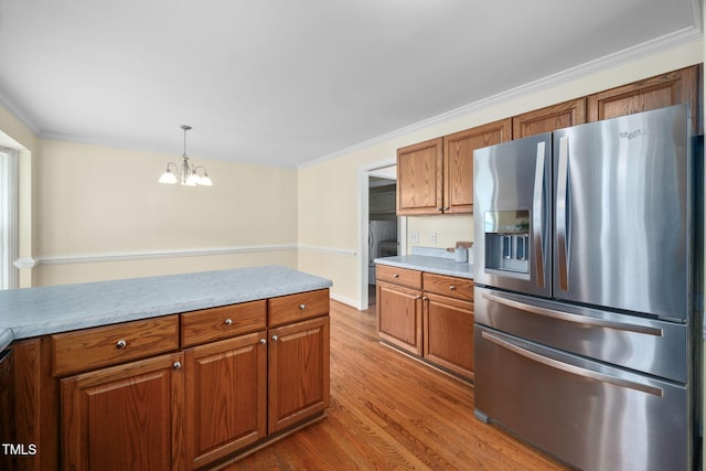 1010 Oakgrove Dr, Knightdale, NC 27545 - kitchen with stainless steel fridge, brown cabinets, a chandelier, wood finished floors, and crown molding