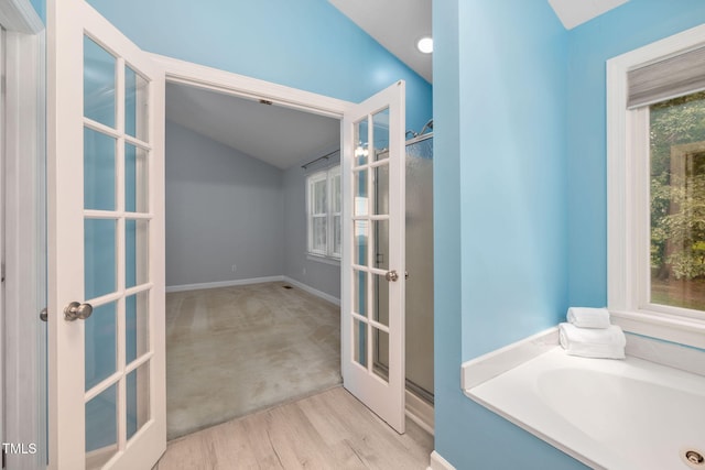 1010 Oakgrove Dr, Knightdale, NC 27545 - full bathroom with french doors, a bath, vaulted ceiling, and wood finished floors