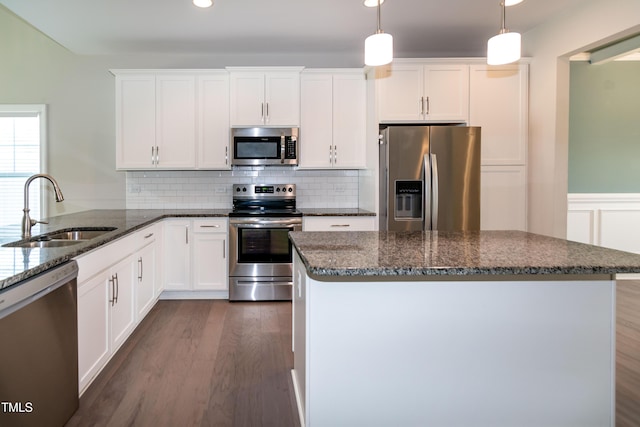 3206 Dandelion Dr, Grimesland, NC 27837 - kitchen with appliances with stainless steel finishes, dark wood-style flooring, dark stone countertops, white cabinets, and wainscoting