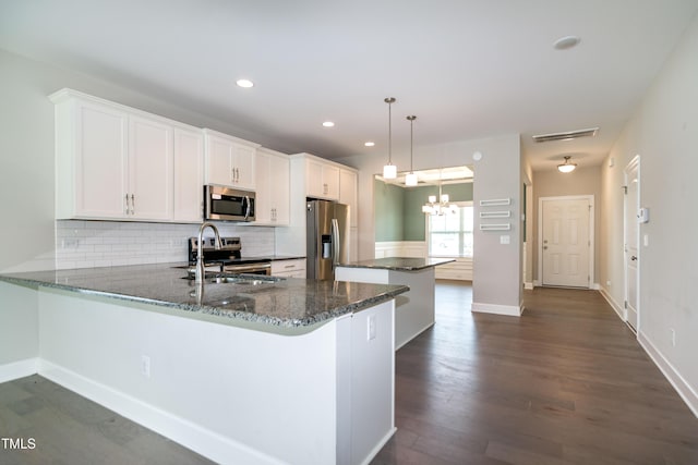 3206 Dandelion Dr, Grimesland, NC 27837 - kitchen with appliances with stainless steel finishes, a kitchen island, decorative backsplash, dark stone counters, and a peninsula