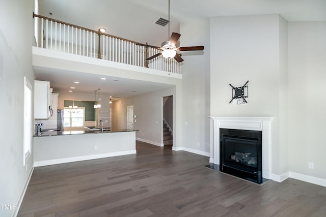 3206 Dandelion Dr, Grimesland, NC 27837 - unfurnished living room featuring a towering ceiling, stairway, dark wood-style floors, a fireplace, and a ceiling fan