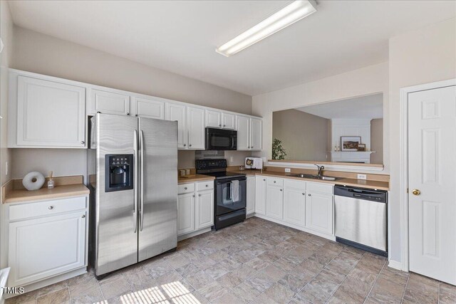 309 Ruby Walk Dr, Morrisville, NC 27560 - kitchen with black appliances, white cabinetry, light countertops, and stone finish floors