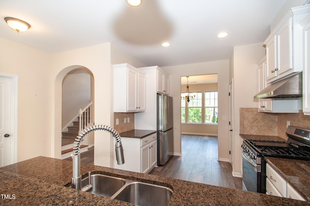 10119 Glen Autumn Rd, Raleigh, NC 27617 - kitchen featuring stainless steel appliances, under cabinet range hood, dark wood-style flooring, dark stone counters, and a chandelier
