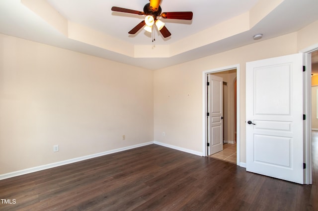 10119 Glen Autumn Rd, Raleigh, NC 27617 - unfurnished bedroom featuring a raised ceiling, dark wood-style flooring, and ceiling fan