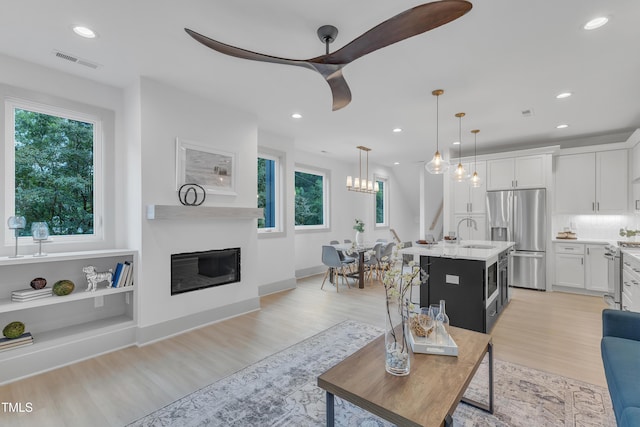1000 Addison Pl Unit 101, Raleigh, NC 27610 - living room with healthy amount of natural light, ceiling fan, light wood-type flooring, a glass covered fireplace, and recessed lighting