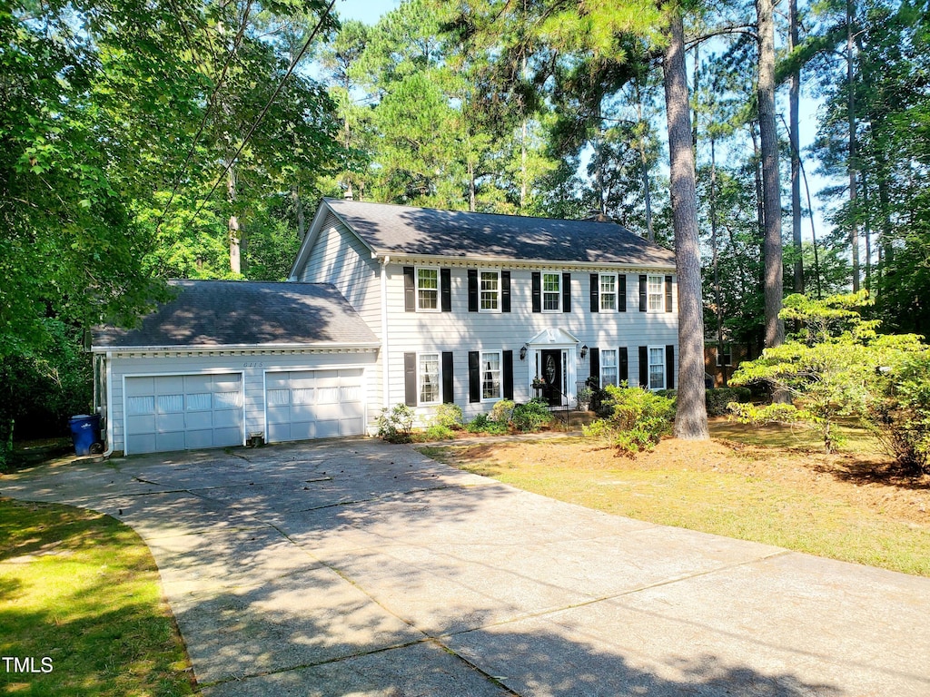 6115 Winthrop Dr, Raleigh, NC 27612 - colonial house with concrete driveway, a garage, and view of scattered trees