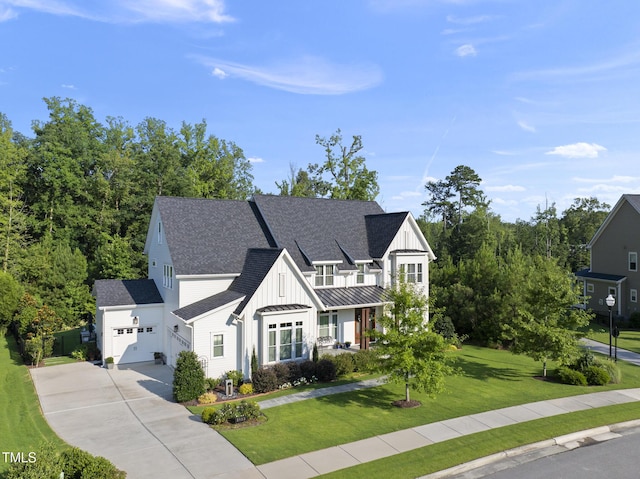 2153 Princeville Dr, Apex, NC 27523 - view of front of property featuring board and batten siding, a front yard, concrete driveway, a shingled roof, and a standing seam roof